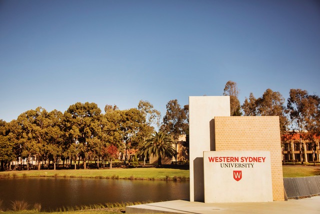 Photograph of the lake and campus, with sign reading Western Sydney University